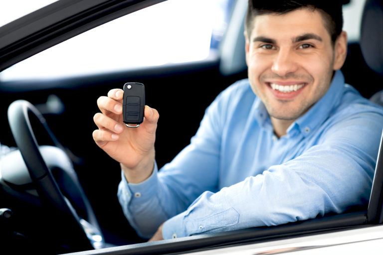 Joyful Businessman Showing Car Key Smiling To Camera Sitting In Driver's Seat In New Automobile Dealership Store